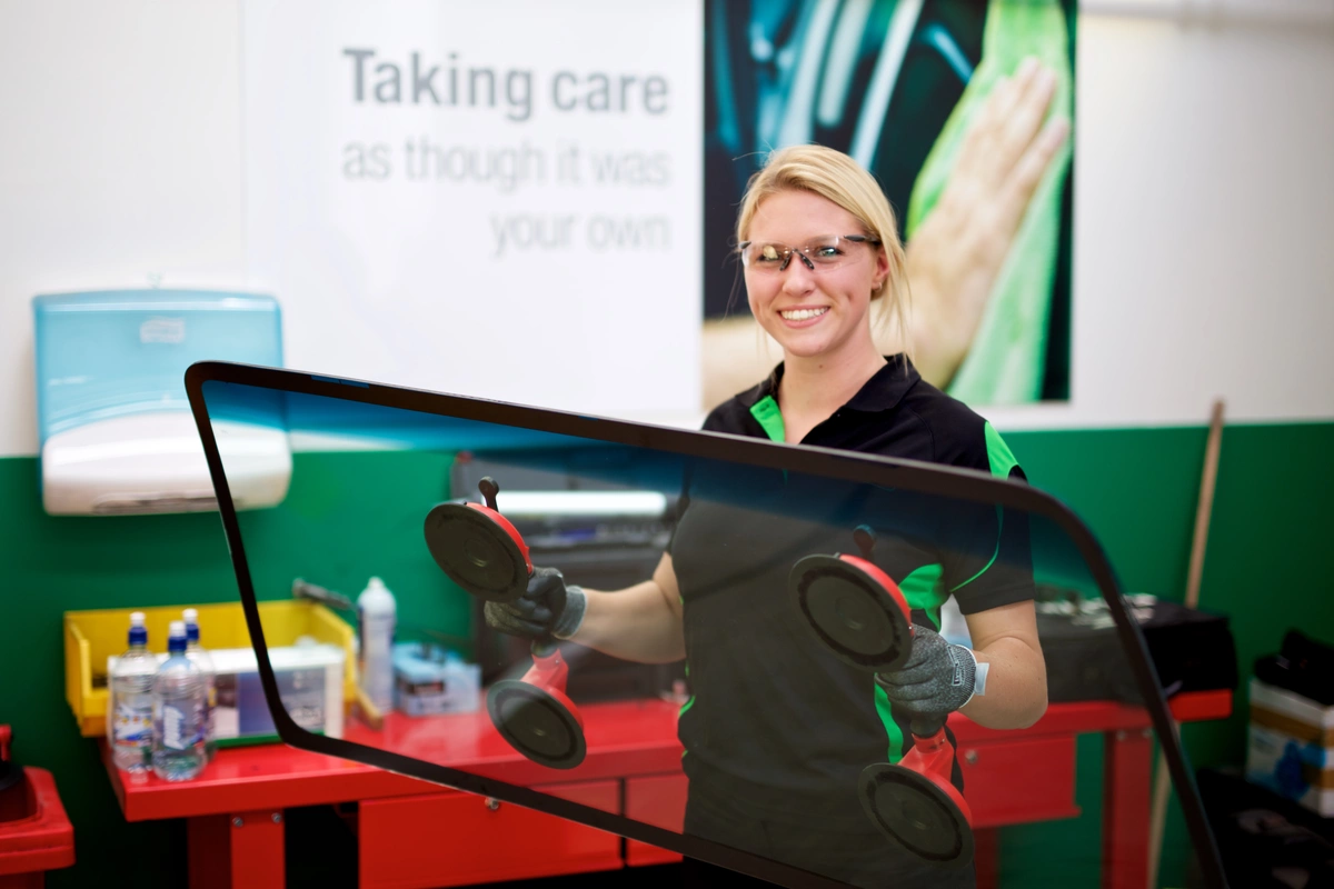Technician holding a new windscreen with suction lifters
